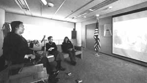 谷井さんの米国視察の写真を大画面で見る3氏の写真